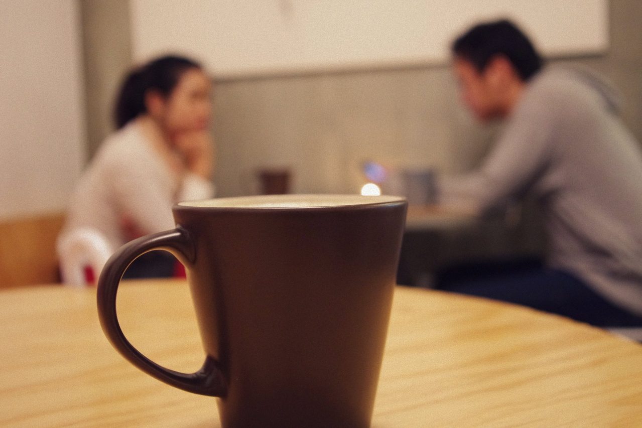 Two people in a seated conversation across a table during a consultation